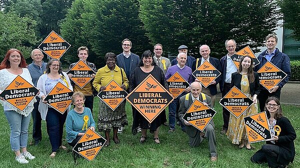 Lib Dem volunteers holding "Winning Here" signs